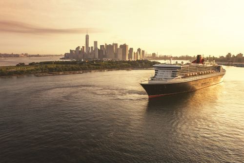 Ein großes Kreuzfahrtschiff fährt bei Sonnenuntergang auf die Skyline von New York zu.